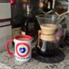 Get Out Of My House Mug from Stone And Broom next to a pour over coffee maker.
